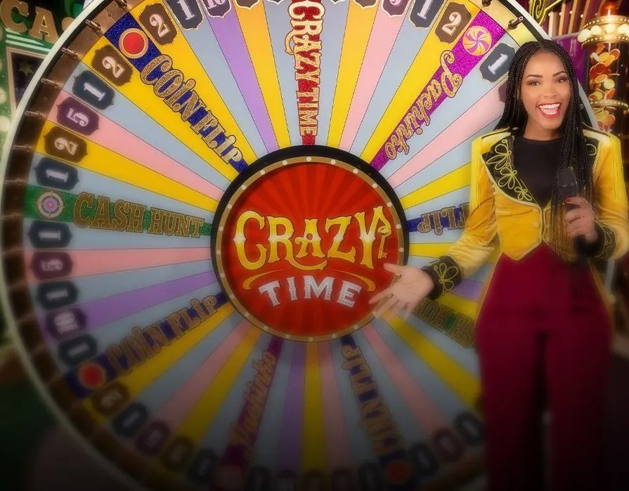La presentatrice di Crazy Time accanto alla grande ruota con il logo del gioco al centro